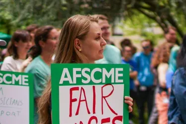 Photo of Oregon AFSCME member holding rally sign that says Fair Wages for All