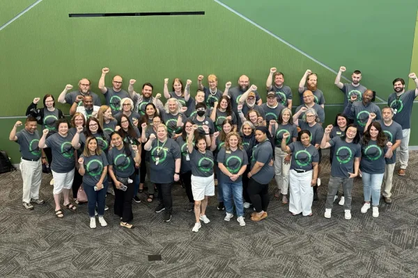 Workers of College of DuPage standing together with fists raised on a green background