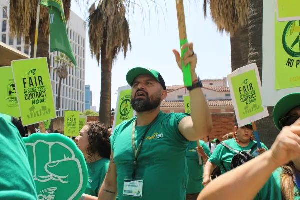 Man in a green AFSCME shirt holding a sign at a rally