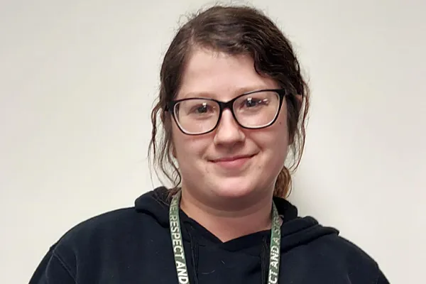 Photo of a white woman with dark hair and glasses smiling.