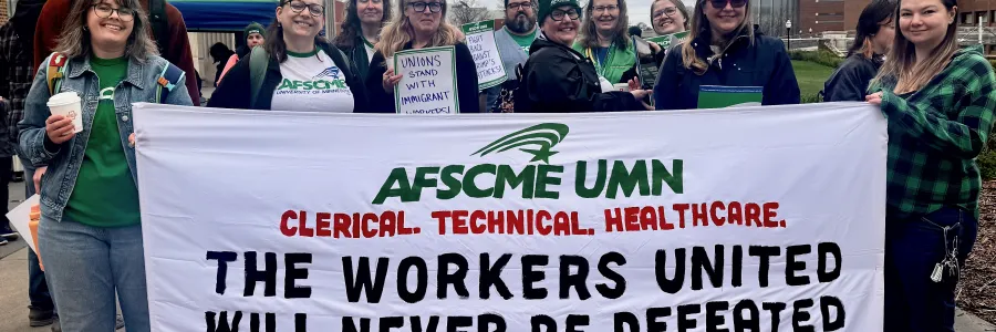 Photo of several AFSCME members holding a sign that says The Workers United Will Never Be Defeated, When We Fight, We Win