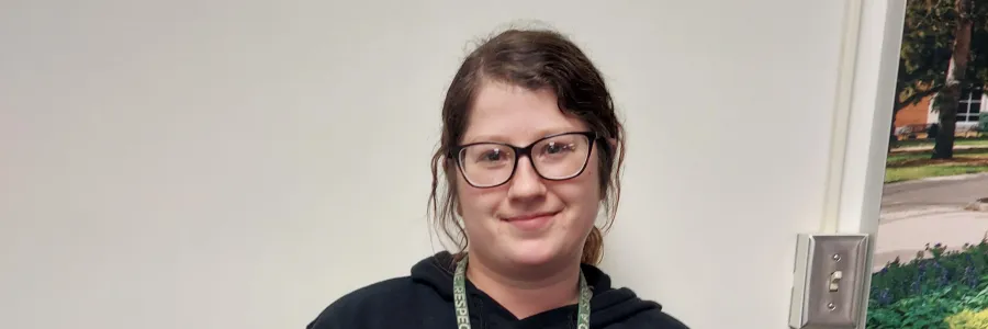 Photo of a white woman with dark hair and glasses smiling.