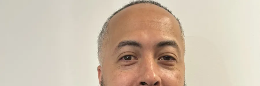 Photo of Black man with a beard and goatee in a blue jacket