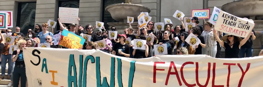 Photo of workers in from of the Art Institute of Chicago holding a large banner that says SAIC and AICWU Faculty Unions