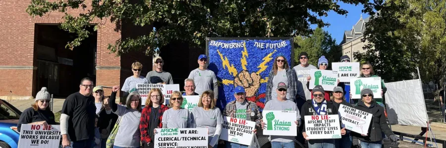 Members of AFSCME Local 981 holding signs about supporting University staff that make the campus run