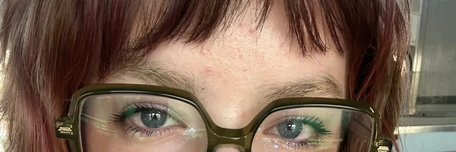 Photo of a white person with shoulder lenth hair and large black rimmed glasses