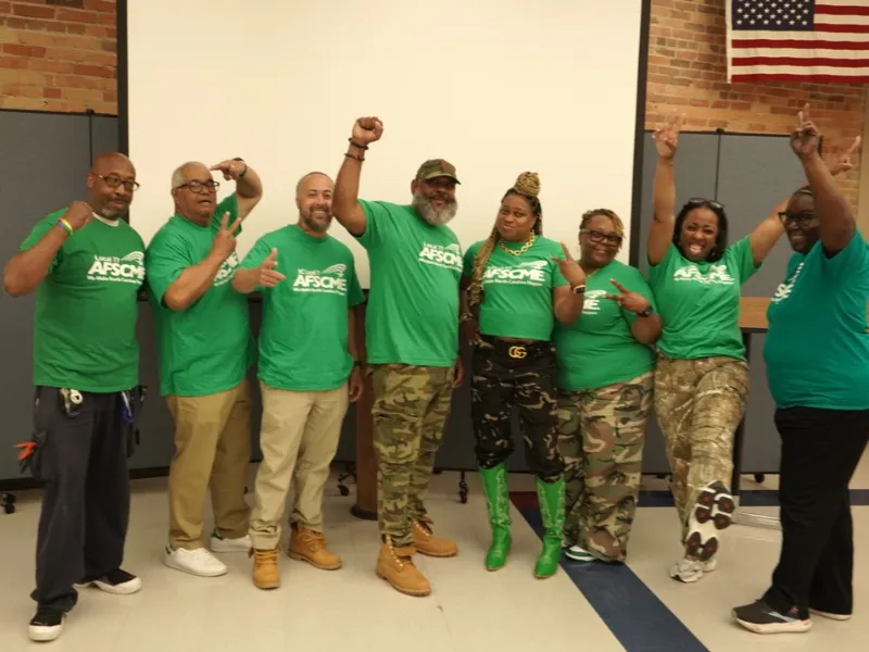 AFSCME Members in green shirts looking triumphant