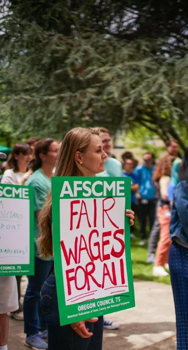 Photo of Oregon AFSCME member holding rally sign that says Fair Wages for All