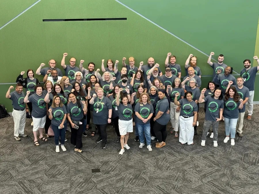 Workers of College of DuPage standing together with fists raised on a green background