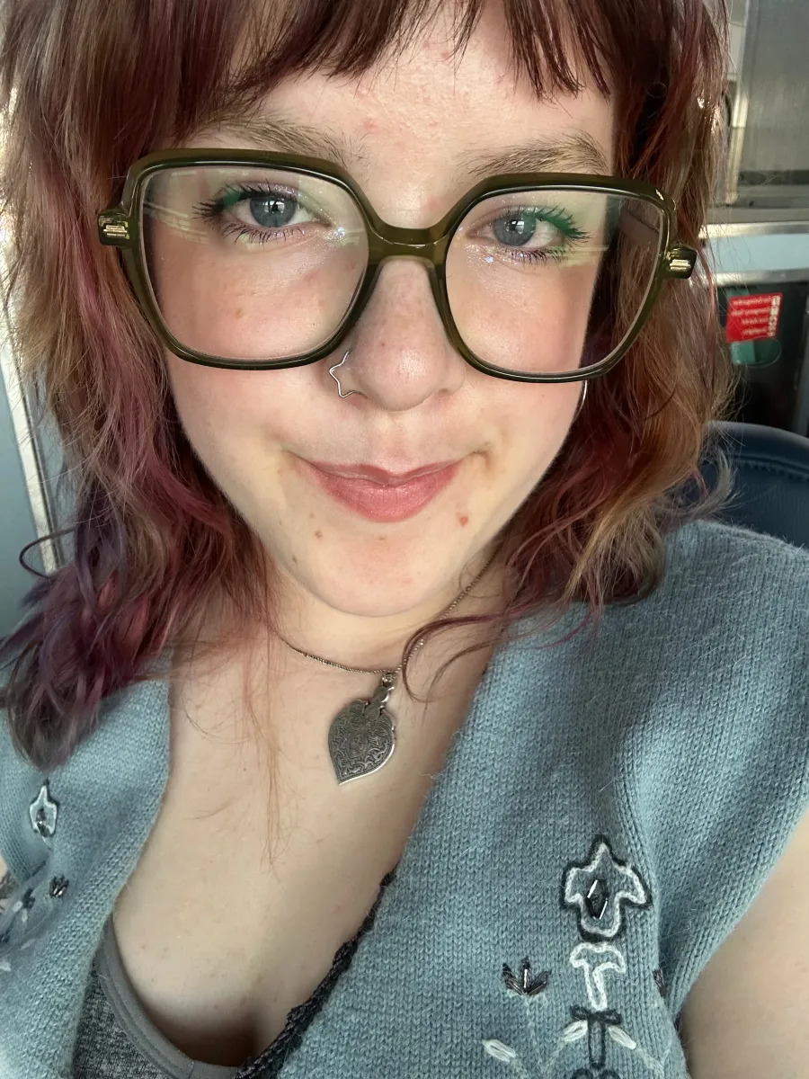 Photo of a white person with shoulder lenth hair and large black rimmed glasses