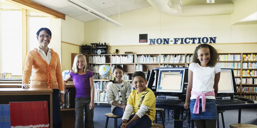 Photo of a teacher with school children in a library setting. Photo credit: Getty Images