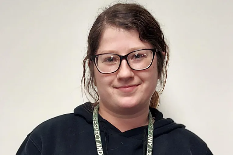 Photo of a white woman with dark hair and glasses smiling.