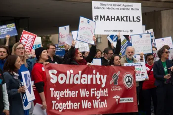 Photo of union higher education staff rallying together with a sign that says "Solidarity! Together we fight! Together we win!"